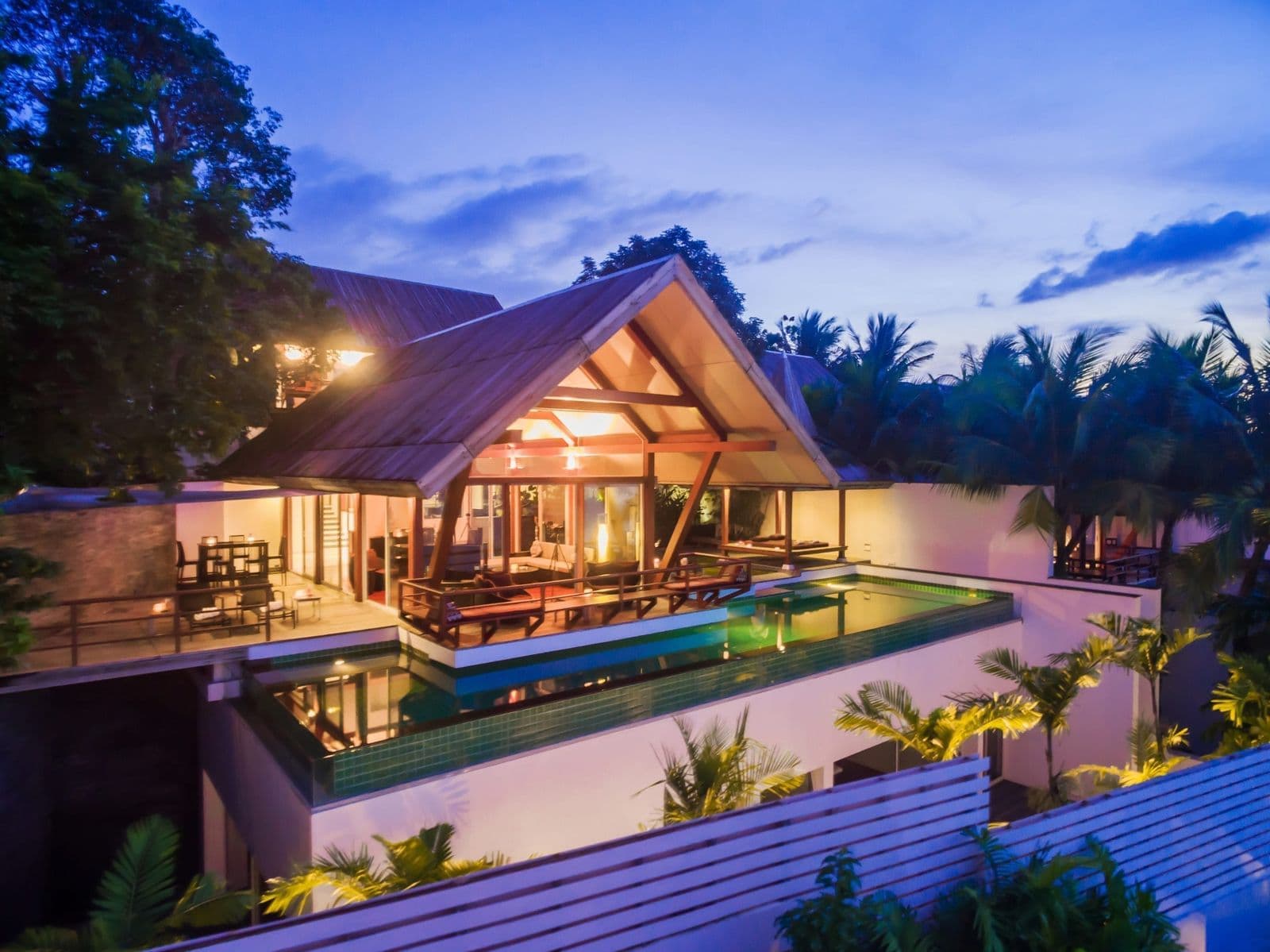 Pool villa with a Thai-style roof and infinity pool at dusk in Surin, Phuket